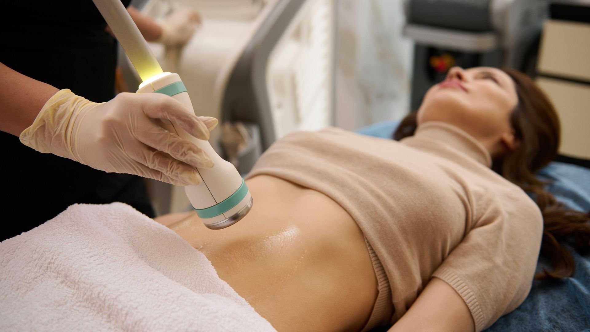 Cosmetic laser treatment on patient's abdomen in medical spa
